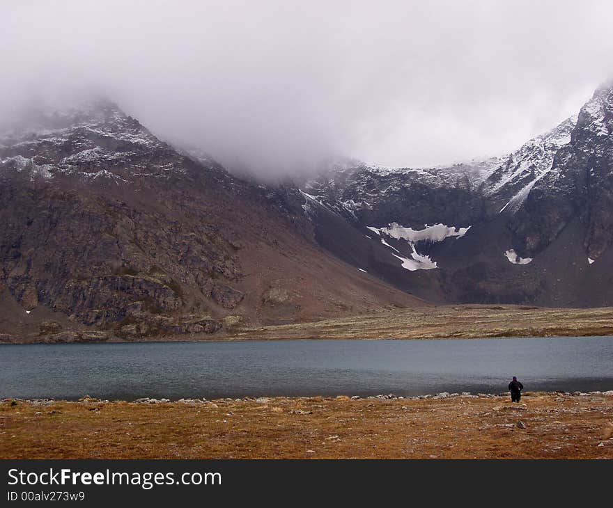 Alpine lake surrounded by knife edged mountain ridge dusted with snow