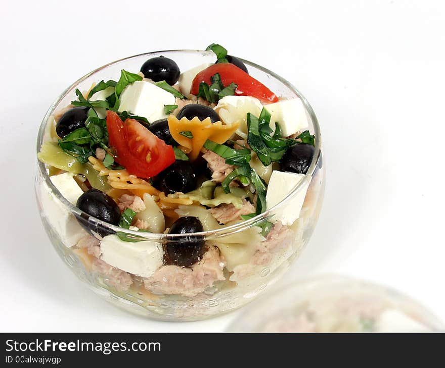 Pasta salad on glass bowl with fetta cheese and olives with soft reflection