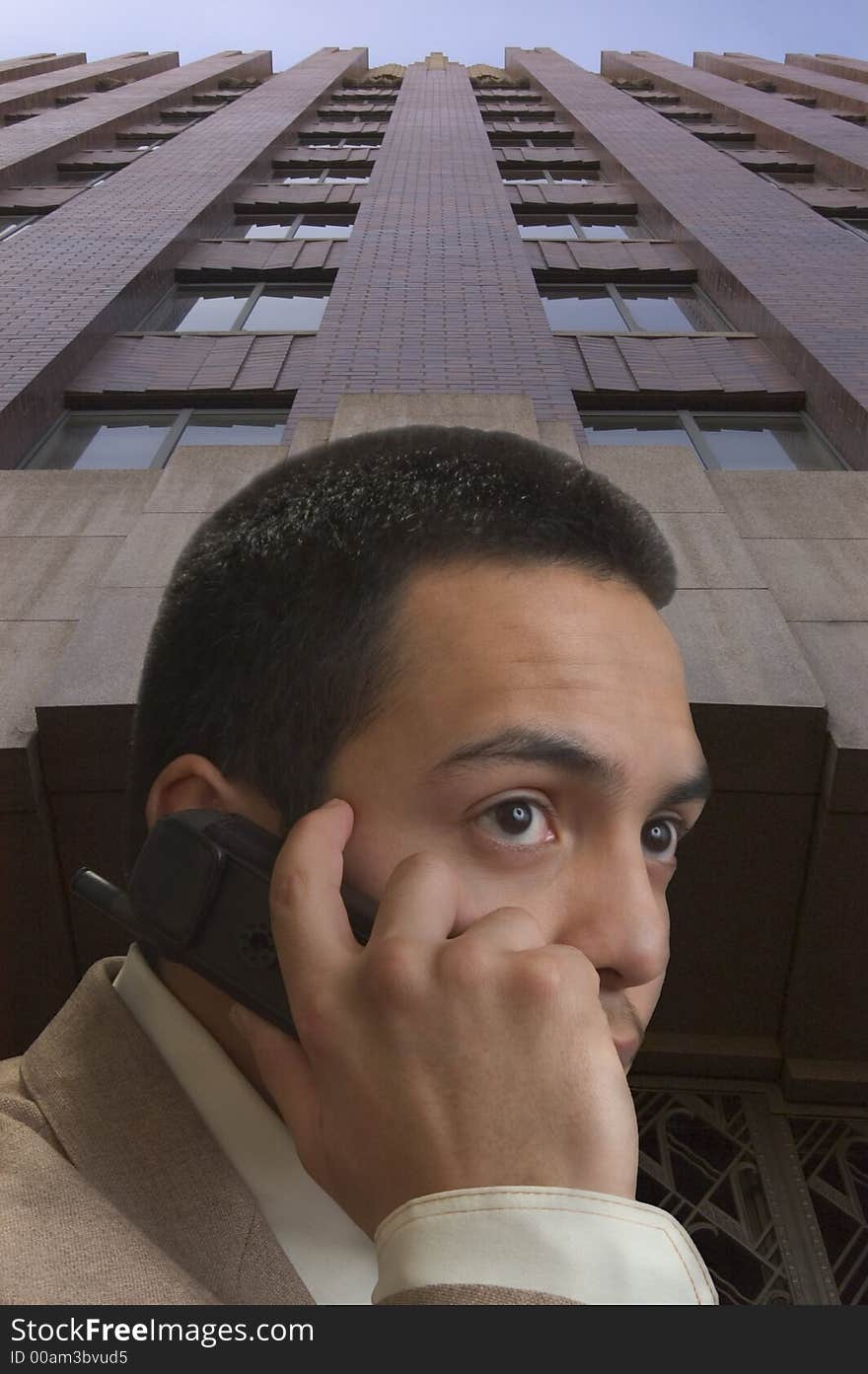 A young hispanic male on cell phone against office building. A young hispanic male on cell phone against office building