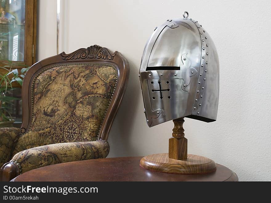 A medieval helmet on a table between chairs