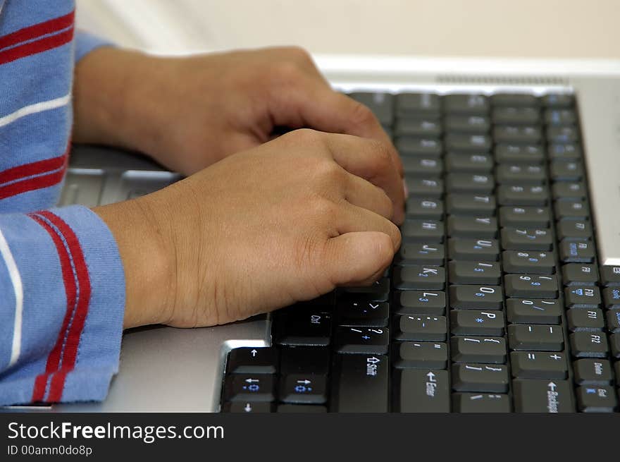 A kid typing his homework on a laptop. A kid typing his homework on a laptop