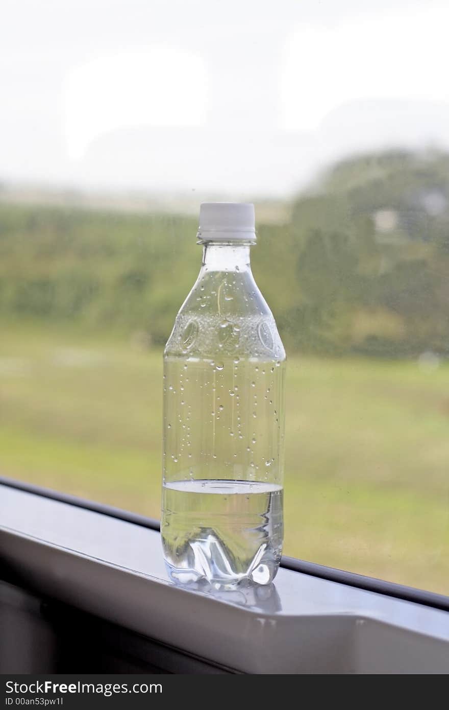 A bottle with mineral water on the jamb in a train in speedy motion. A bottle with mineral water on the jamb in a train in speedy motion.