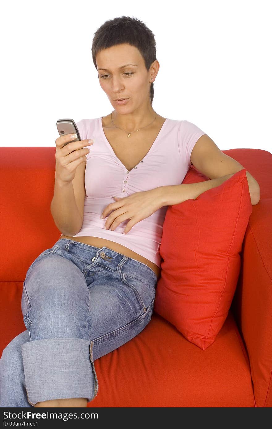 Woman looking at the mobile; sitting on the red sofa. Woman looking at the mobile; sitting on the red sofa