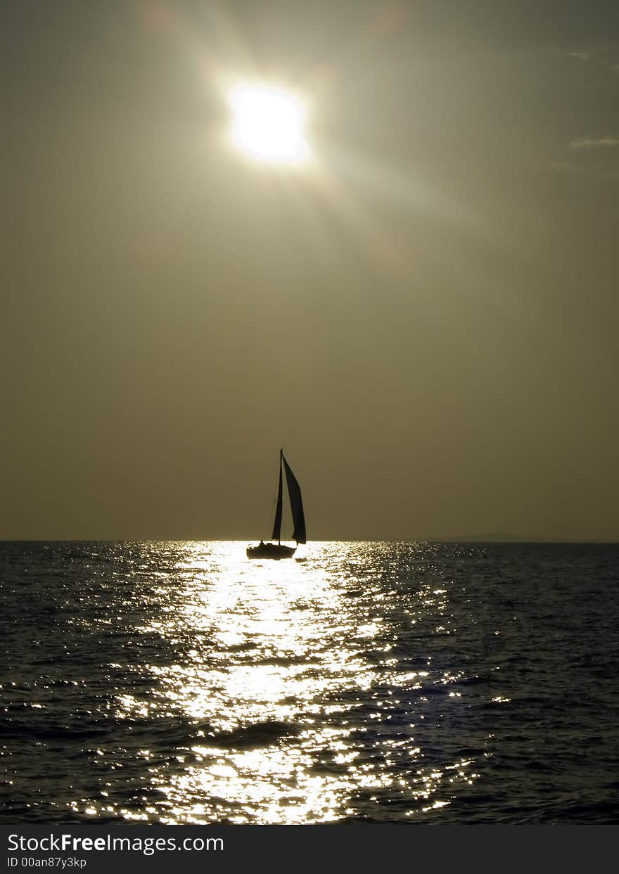 Sailing yacht in a light wind travelling against the golden afternoon sun. Sailing yacht in a light wind travelling against the golden afternoon sun