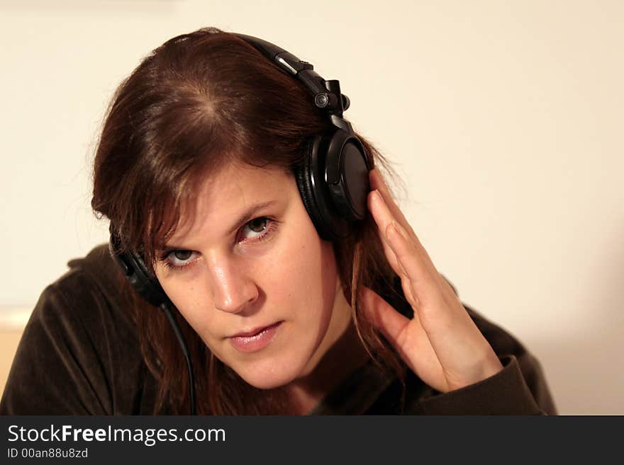 A young female dj is listening to a tune over her headphones.