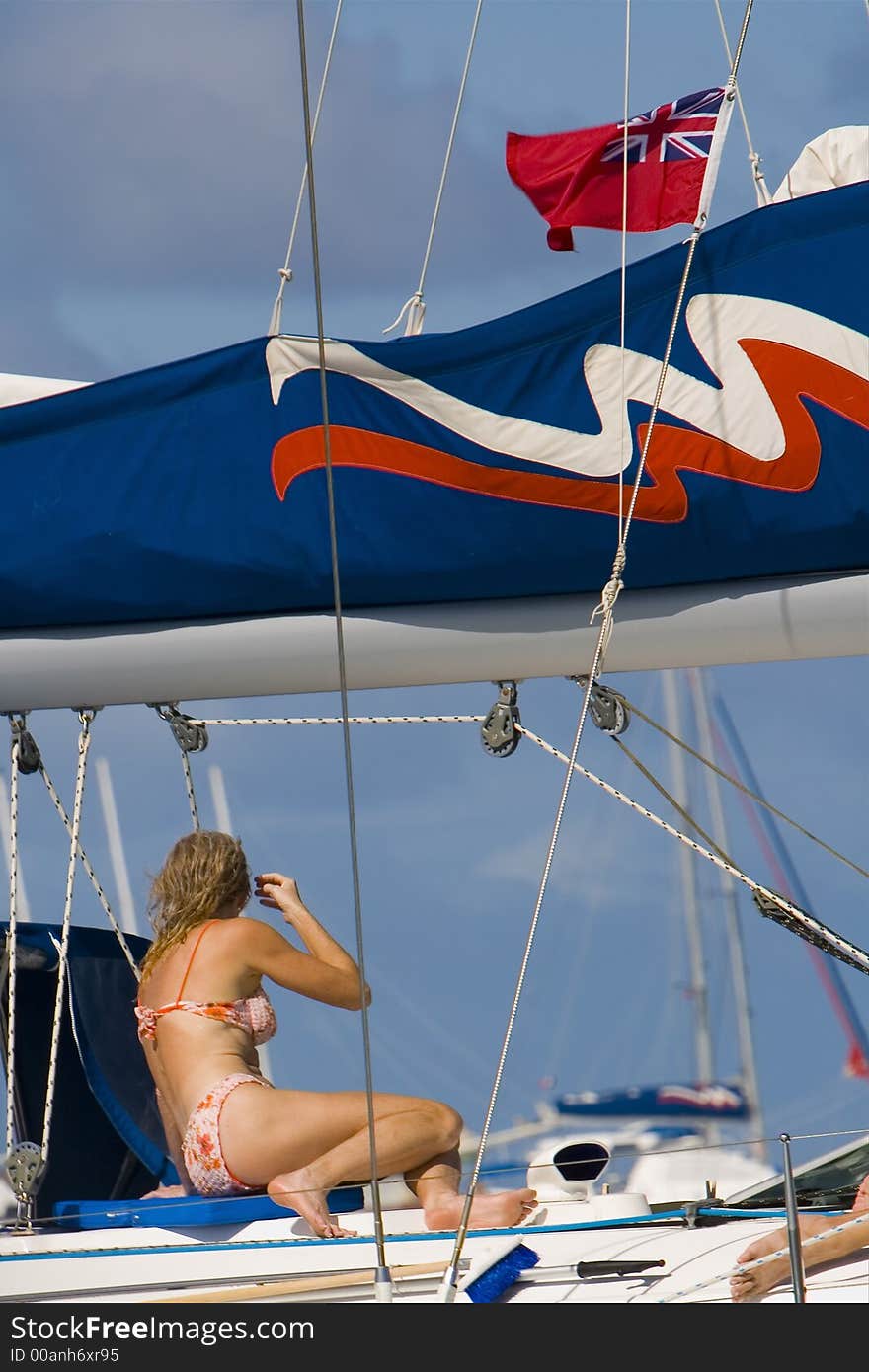 Bikini clad woman catching some rays on a sailboat. Bikini clad woman catching some rays on a sailboat.