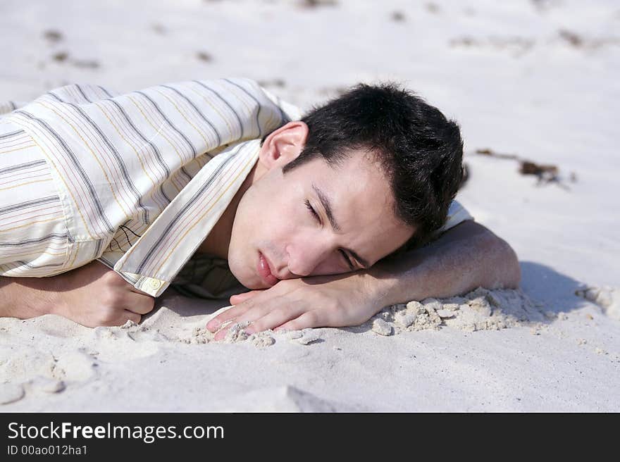 A young man sleeping at the beach