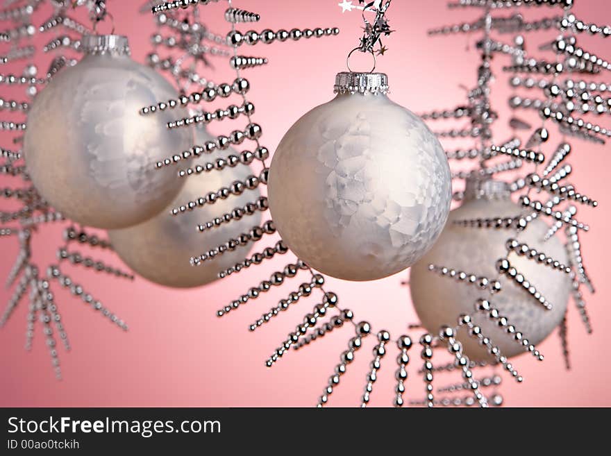 Christmas baubles hanging over pink background