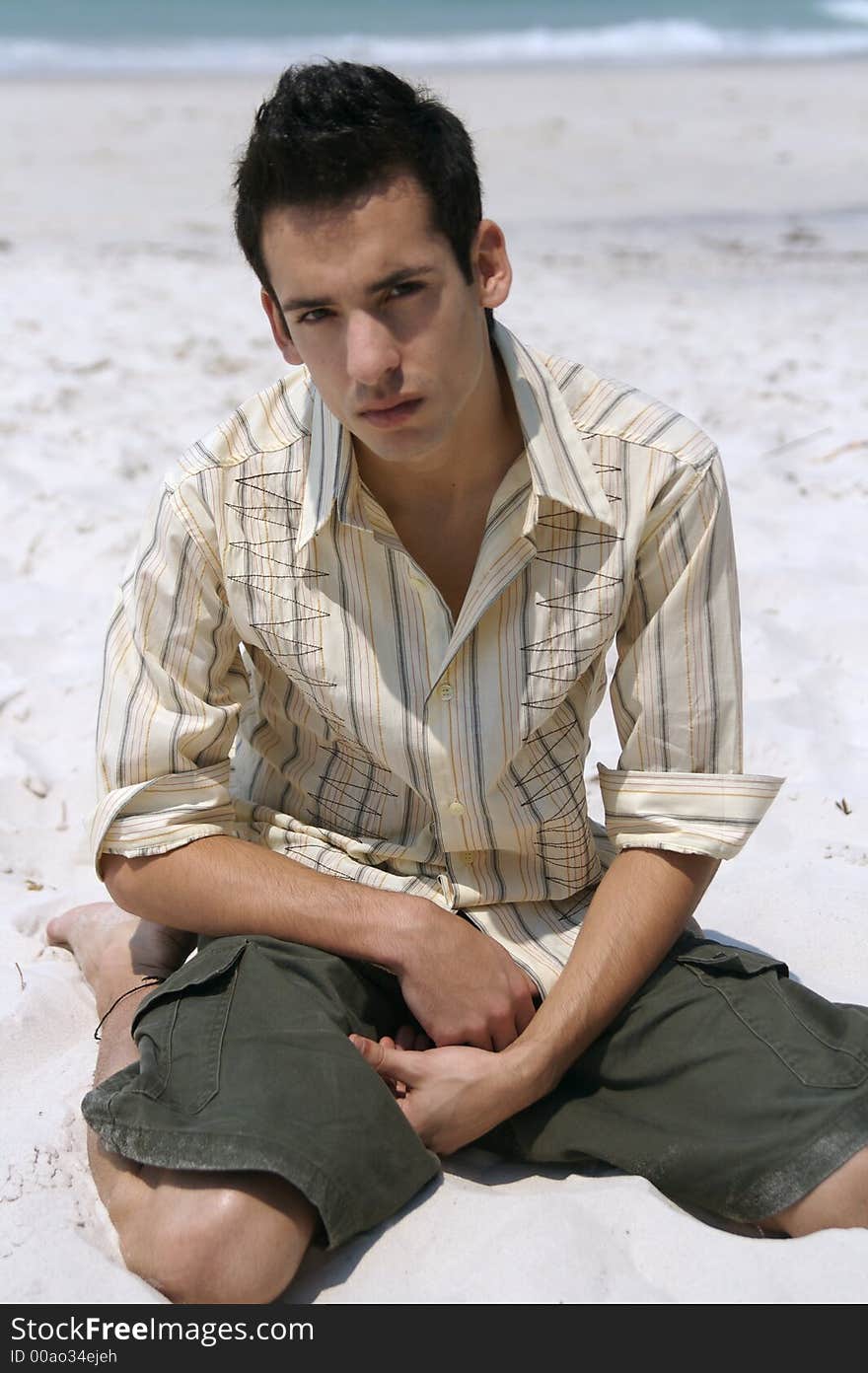 A handsome young man kneeing at the beach