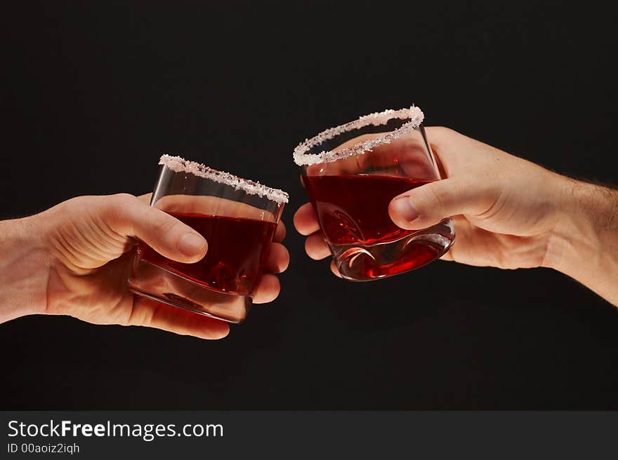 Two hands toasting with cherry brandy glasses on dark background. Two hands toasting with cherry brandy glasses on dark background