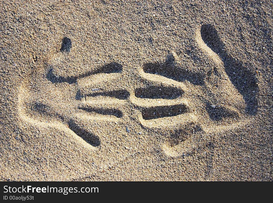 Two handprints in the sand in sunlight