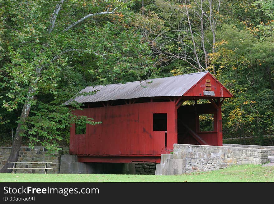 Classic Red Covered Bridge in a rural setting in early Autumn. Classic Red Covered Bridge in a rural setting in early Autumn.