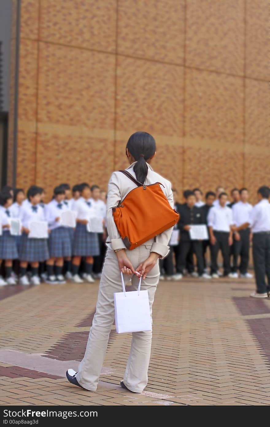 Woman with bags looking to a children chorus show in a city.