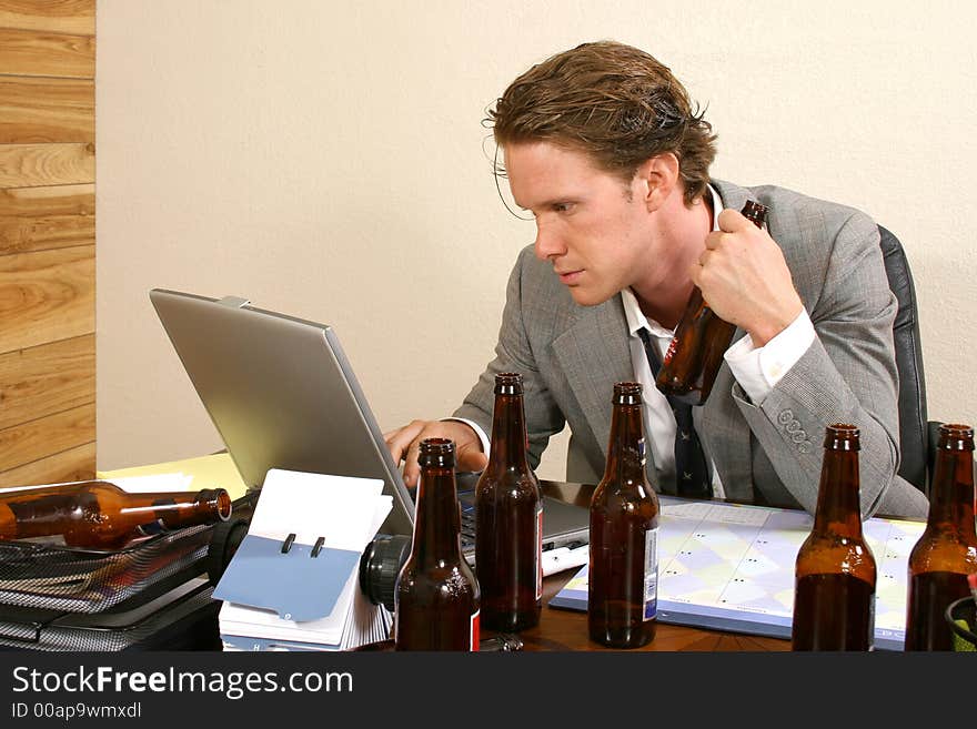 Business man at desk with empty beer bottles. Business man at desk with empty beer bottles.