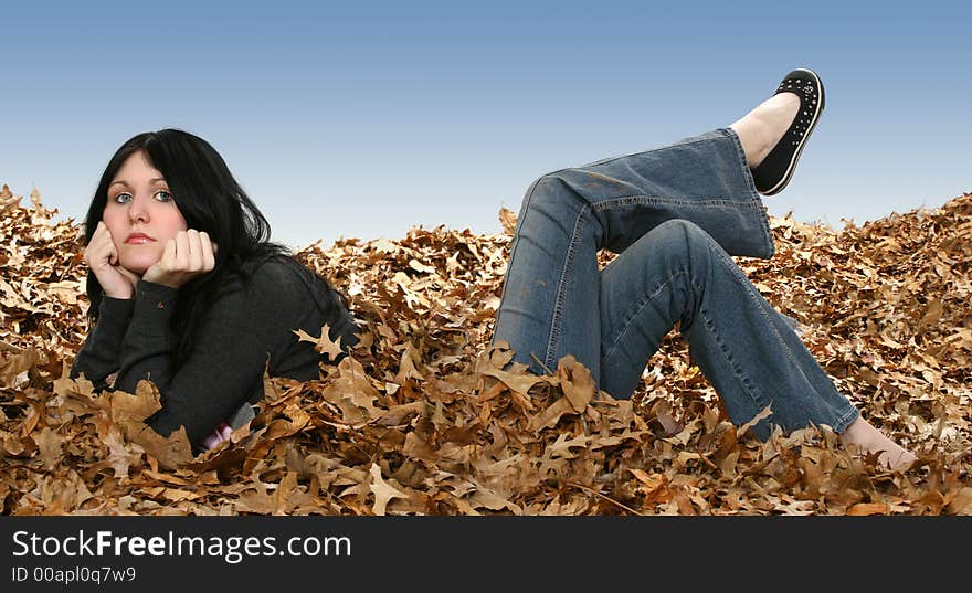 Beautiful teen girl laying in leaves with legs on backwards. Beautiful teen girl laying in leaves with legs on backwards.