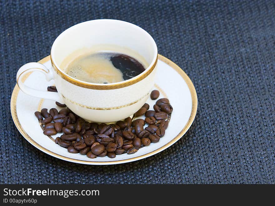 A cup of fine china porcelain , full of coffee, with coffee beans on the side. A cup of fine china porcelain , full of coffee, with coffee beans on the side