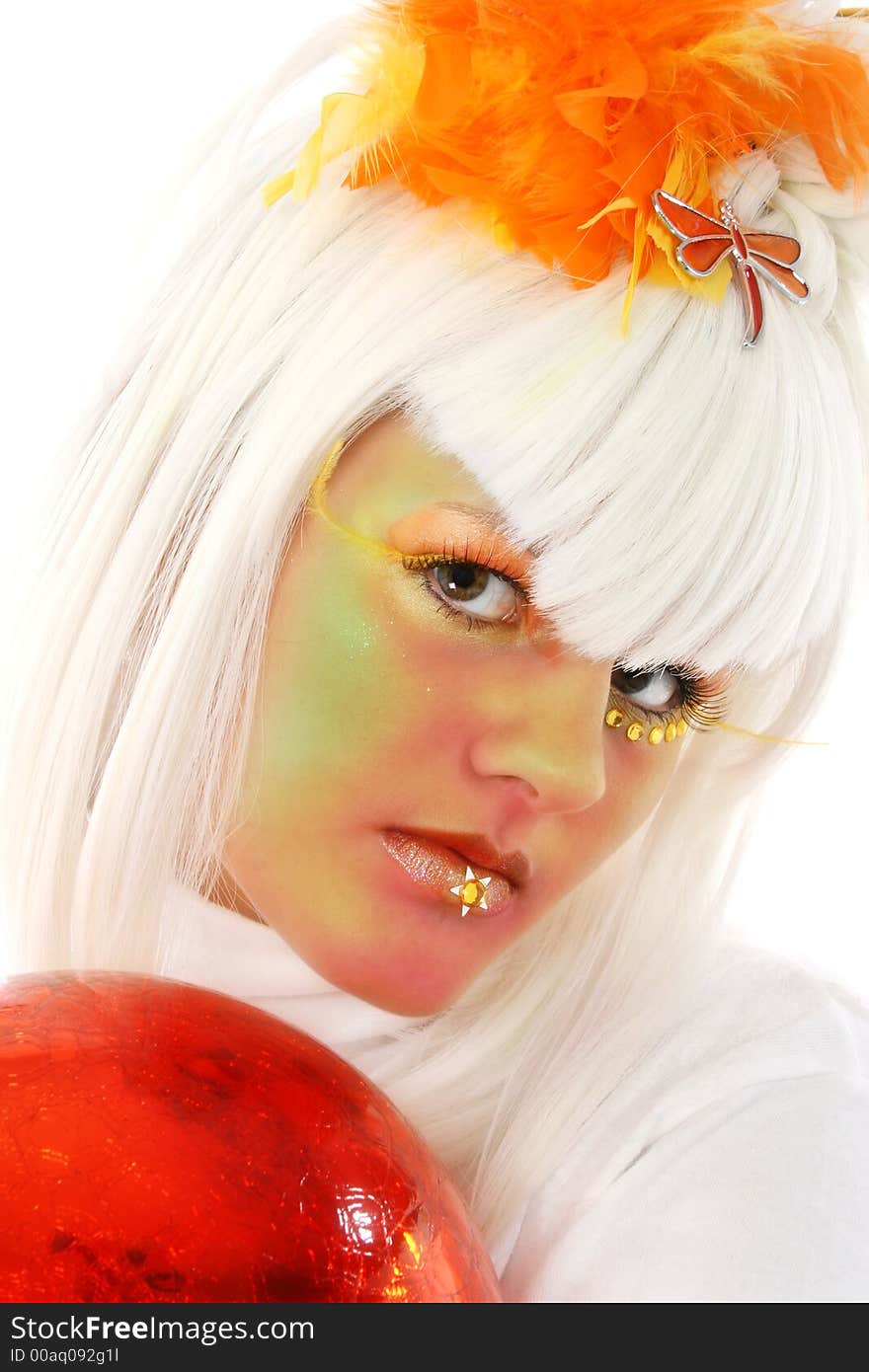 Beautiful young woman in artistic make-up holding orange orb. Beautiful young woman in artistic make-up holding orange orb.