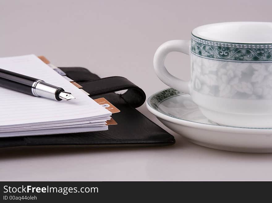 A cup of coffee and organizer with fountain pen. A cup of coffee and organizer with fountain pen.