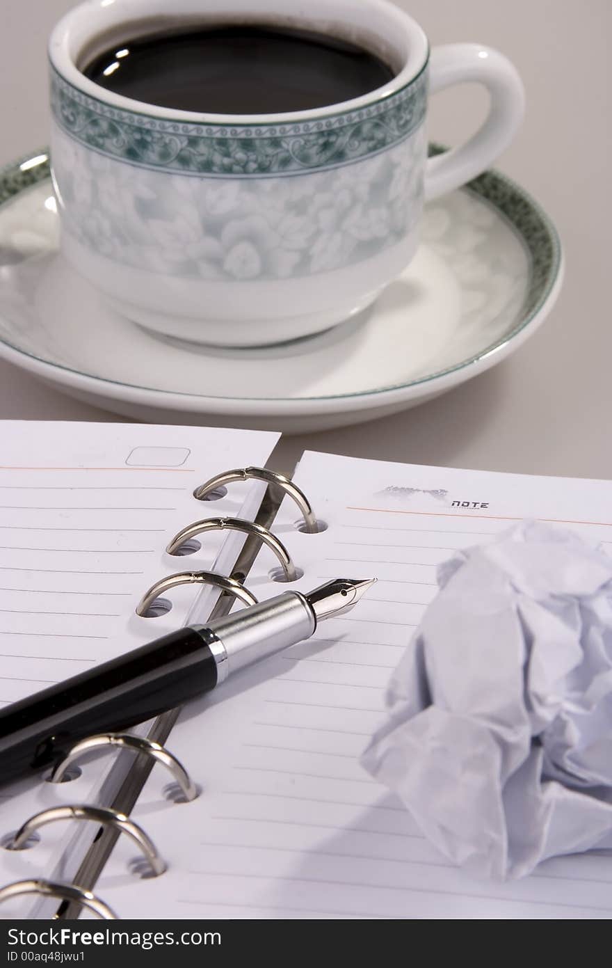 Coffee with crumpled paper, pen and organizer.