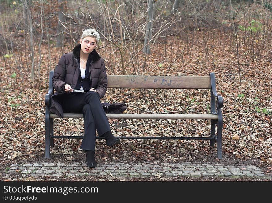 Business woman outdoor in a park reading mails and notebook