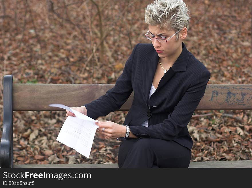 Business woman outdoor in a park reading mails and notebook