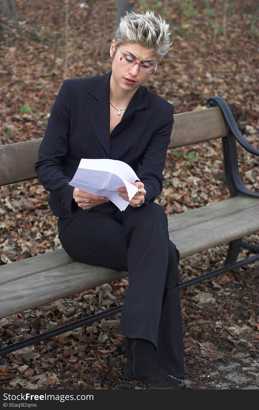 Business woman outdoor in a park reading mails and notebook