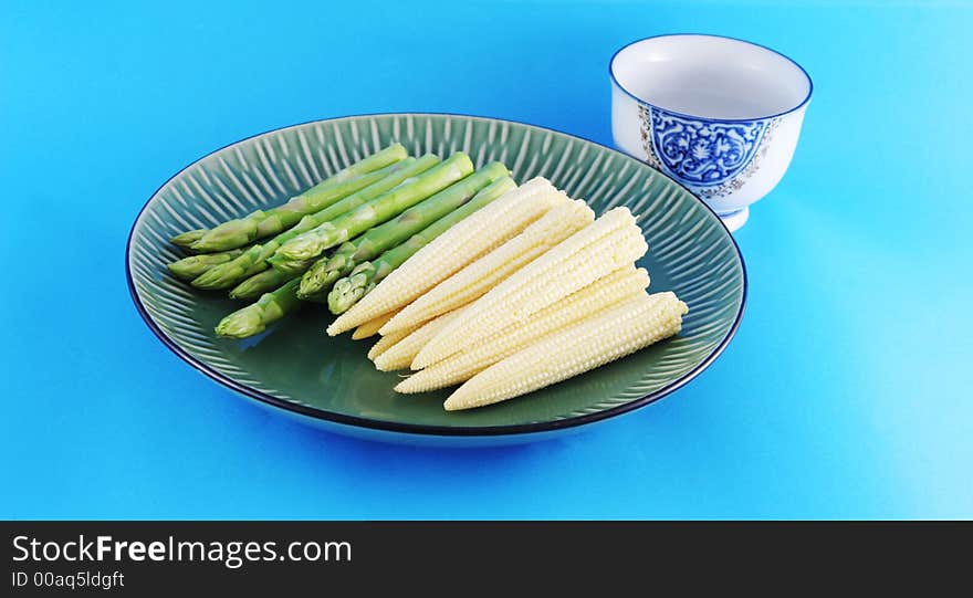 Fresh asparagus shoots and corn on a plate