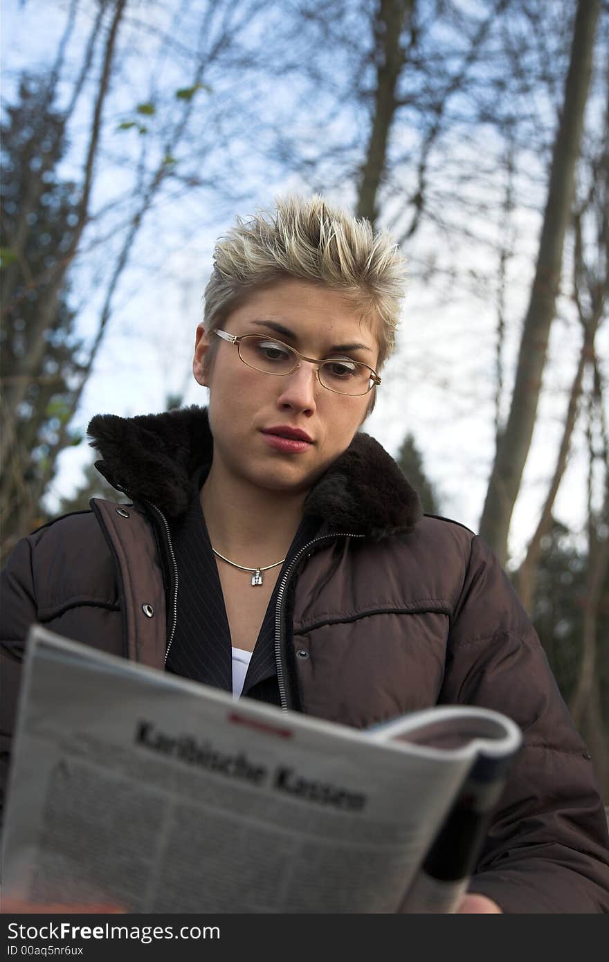 Business woman outdoor in a park reading a magasine