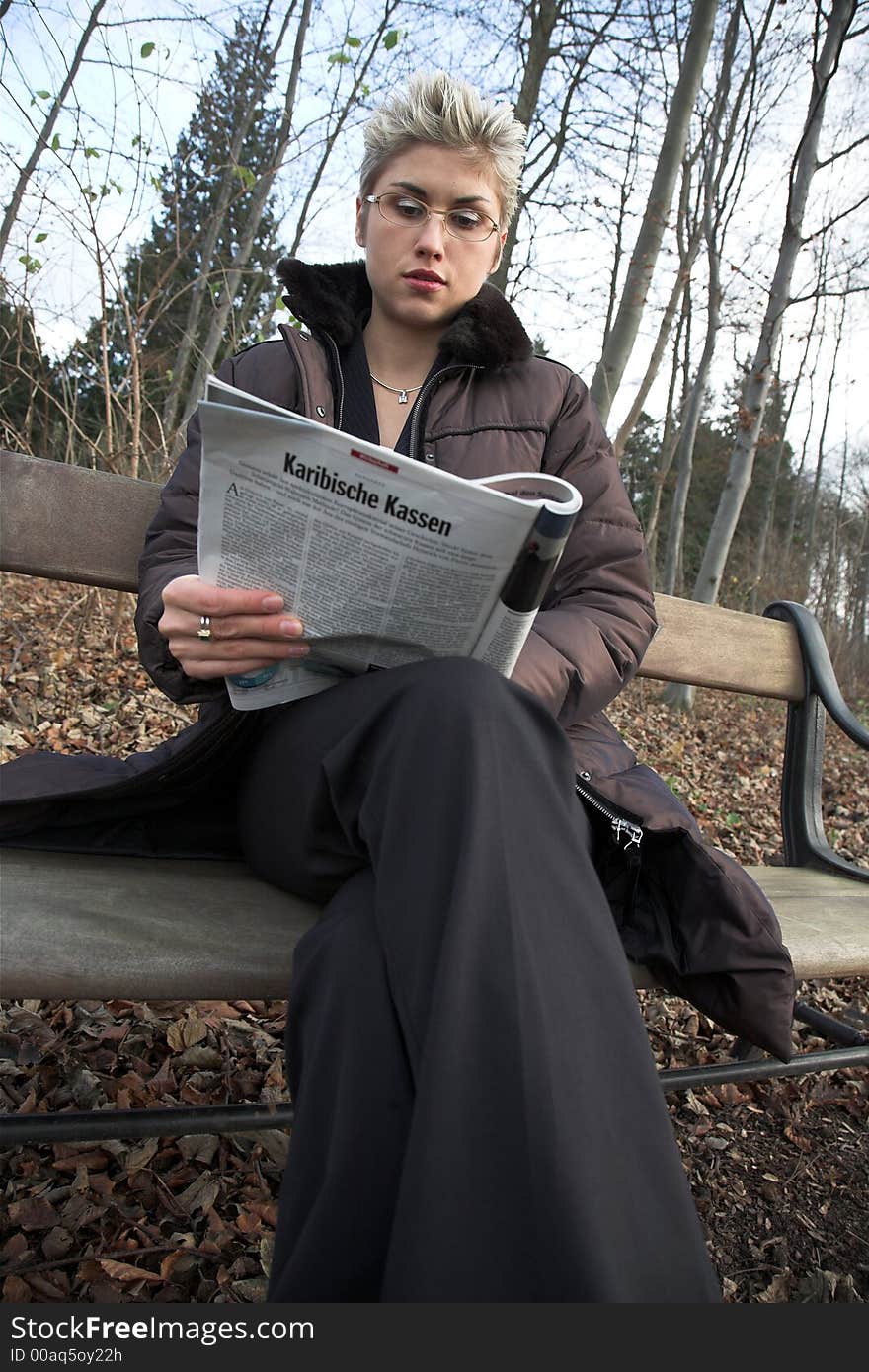 Business woman outdoor in a park reading a magasine