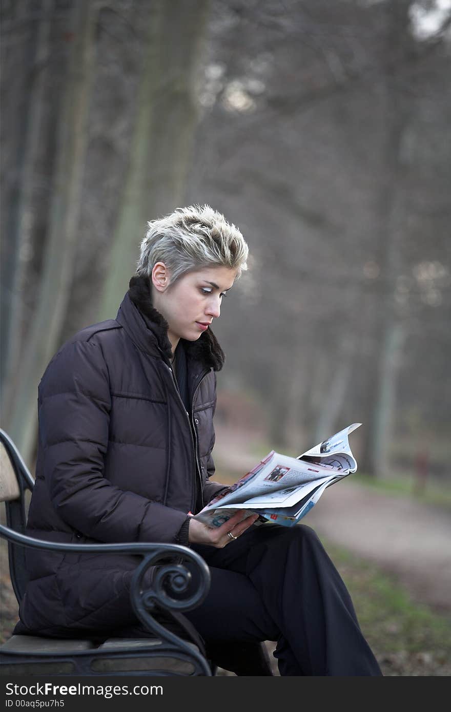 Business woman outdoor in a park reading a magazine