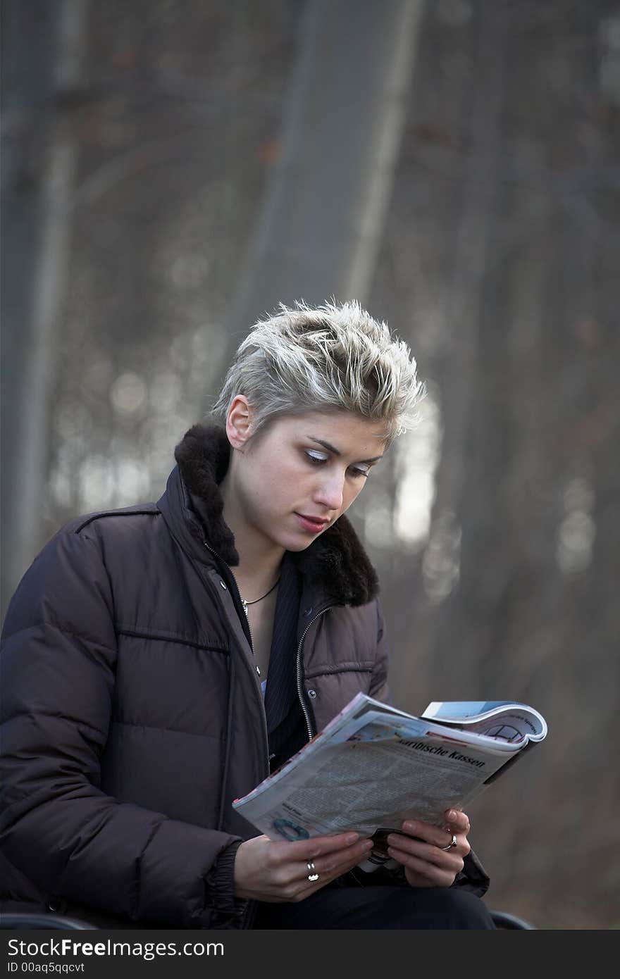 Business woman outdoor in a park reading a magazine