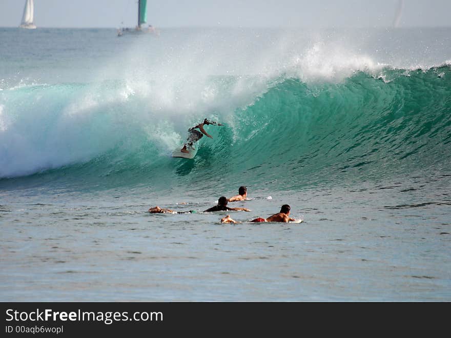 A surfer getting a tube ride while other surfers watch