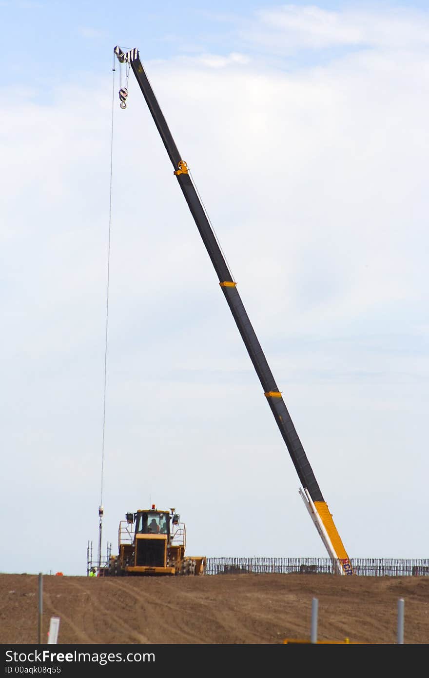 Tall crane with yellow earth mover