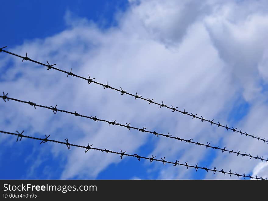 Long barbed wire 3 rows over cloudy sky