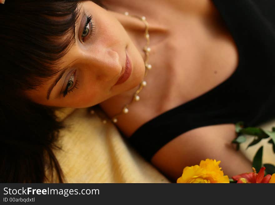 Young black-haired beautiful girl looking at flowers. She is laying on a sofa and dreaming about love. Young black-haired beautiful girl looking at flowers. She is laying on a sofa and dreaming about love.