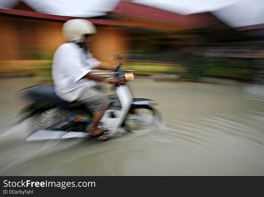 A man rides a motorcycle through a flooding street, motion blur. A man rides a motorcycle through a flooding street, motion blur