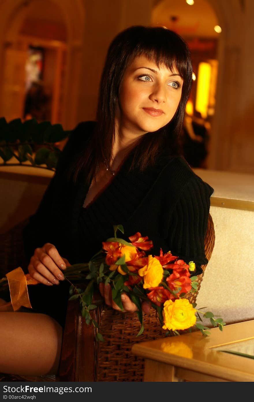 Stylish girl with a bunch of flowers sitting on a sofa. Stylish girl with a bunch of flowers sitting on a sofa