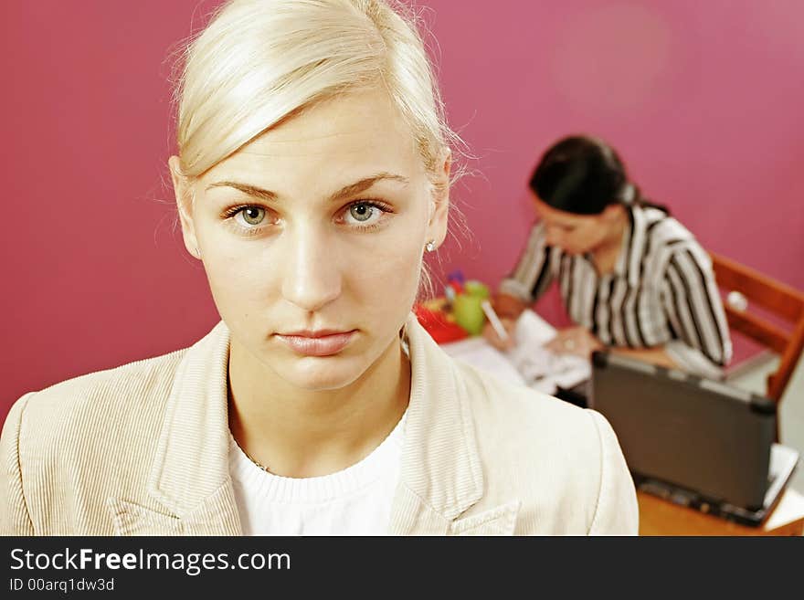 Businesswoman and a secretary over some paperwork in modern office-on pink