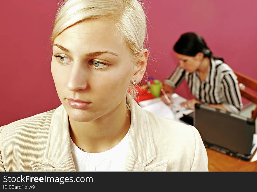 Businesswoman and a secretary over some paperwork in modern office-on pink