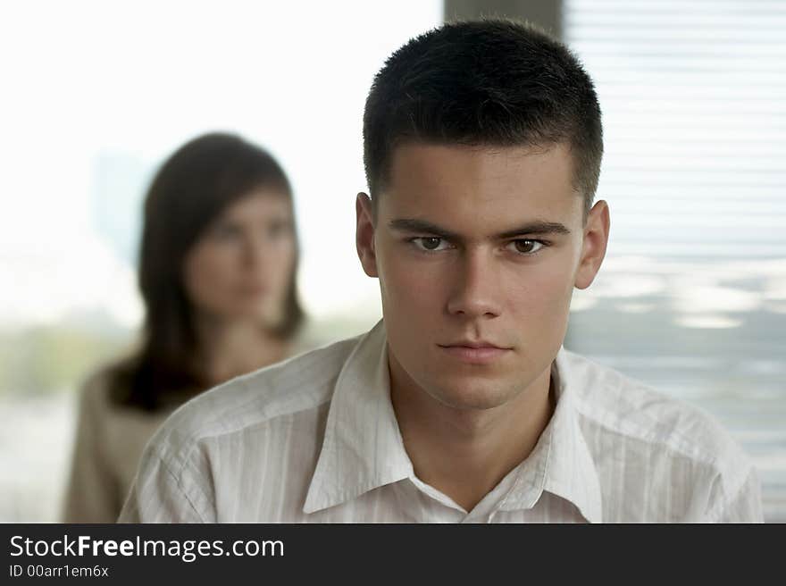 Portrait of young, good-looking man in white shirt with blurred woman in the background. Portrait of young, good-looking man in white shirt with blurred woman in the background