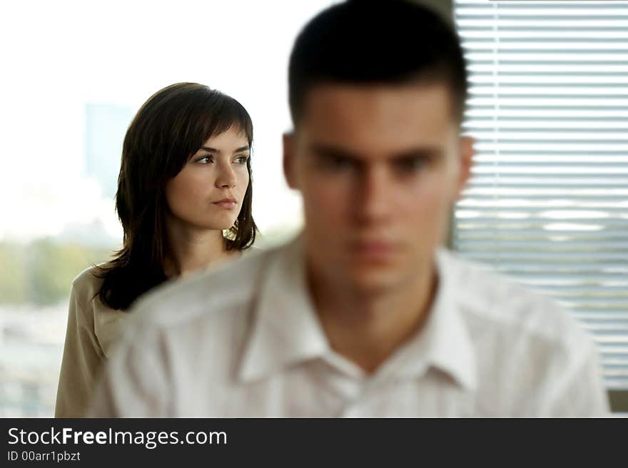 Portrait of young, good-looking man in white shirt with blurred woman in the background. Portrait of young, good-looking man in white shirt with blurred woman in the background