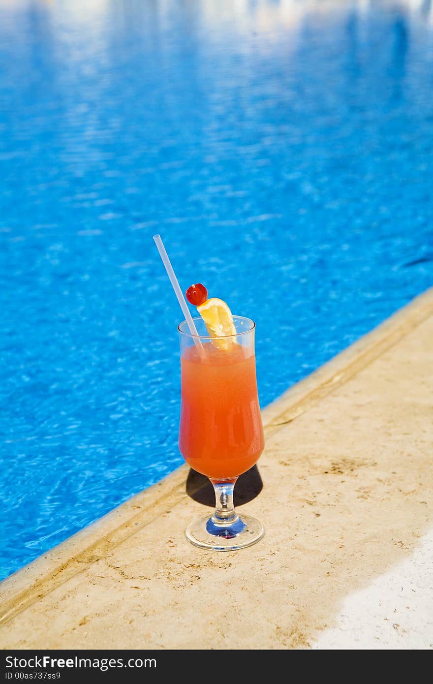 Cocktail stands on edge of pool. as a symbol of a rest.