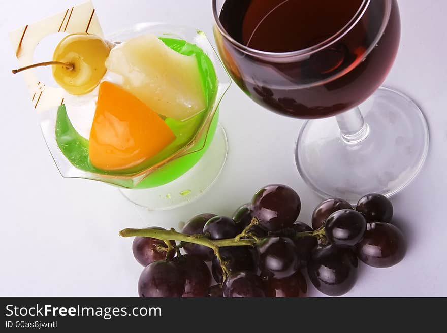 Close up of red wine with grapes and dessert.