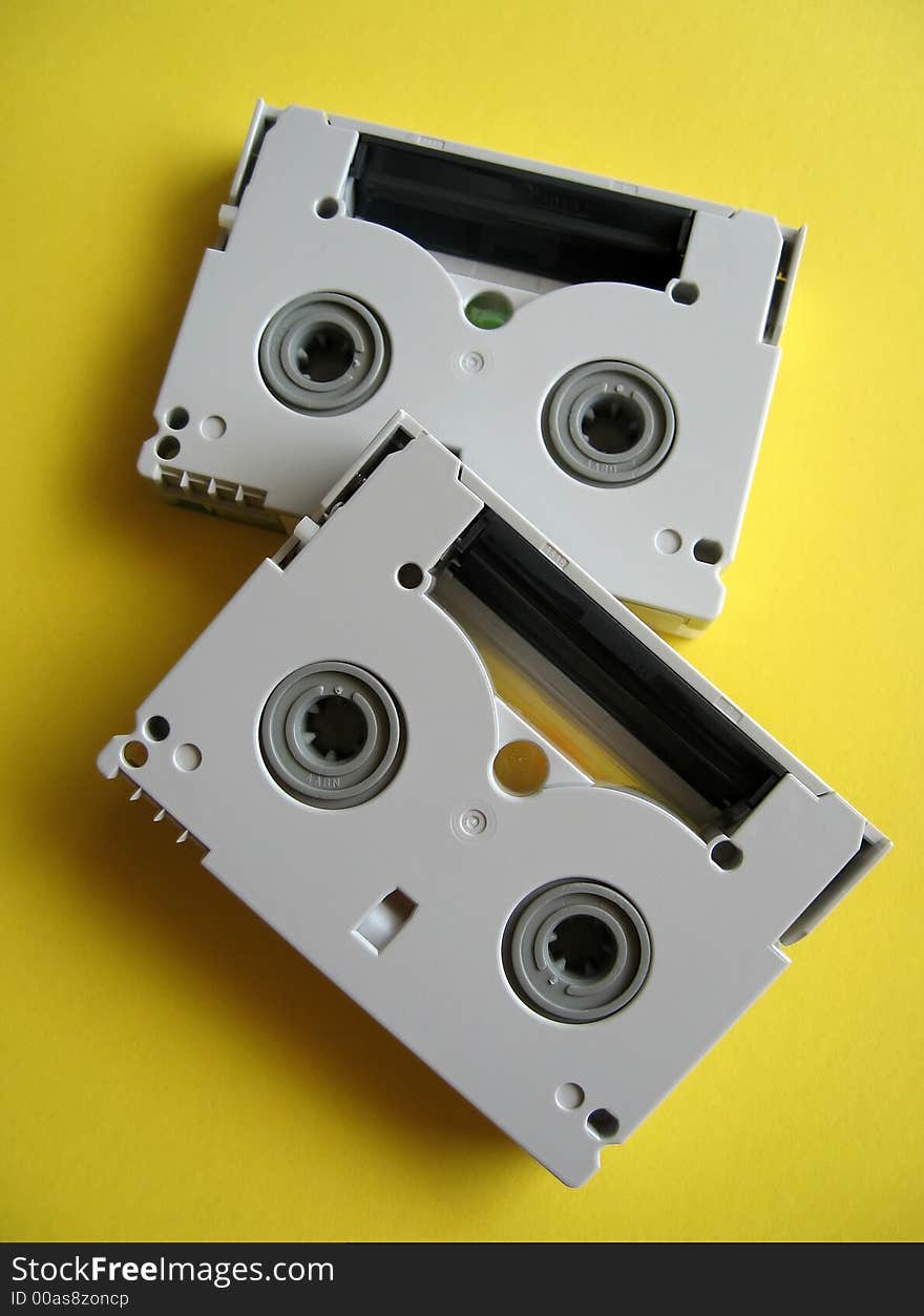 Mini DV tapes on yellow paper background.