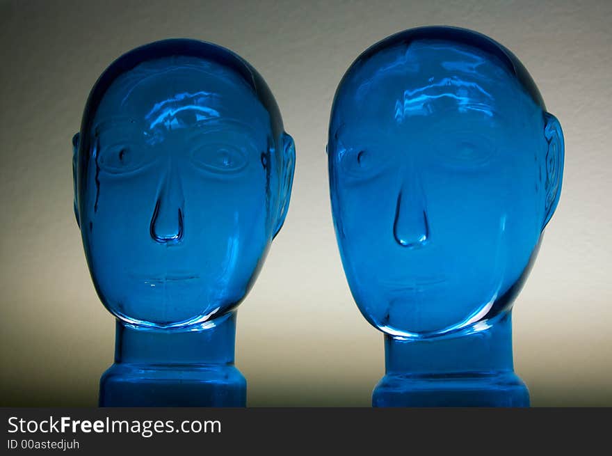 Two glass dark blue heads on a neutral background