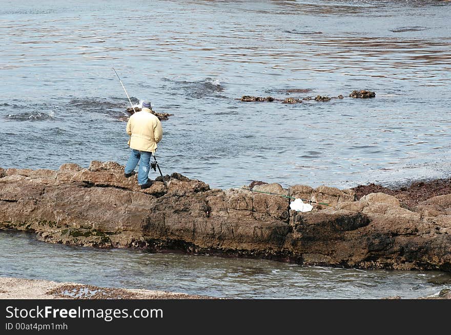 Man fishing alone over rocks in front of sea. Man fishing alone over rocks in front of sea