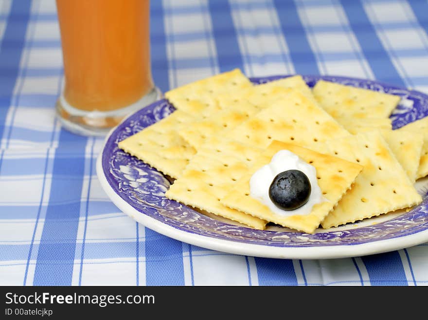 Plate with crackers,yogurt,blueberry and a glass of orange juice-good choice for a healthy breakfast.