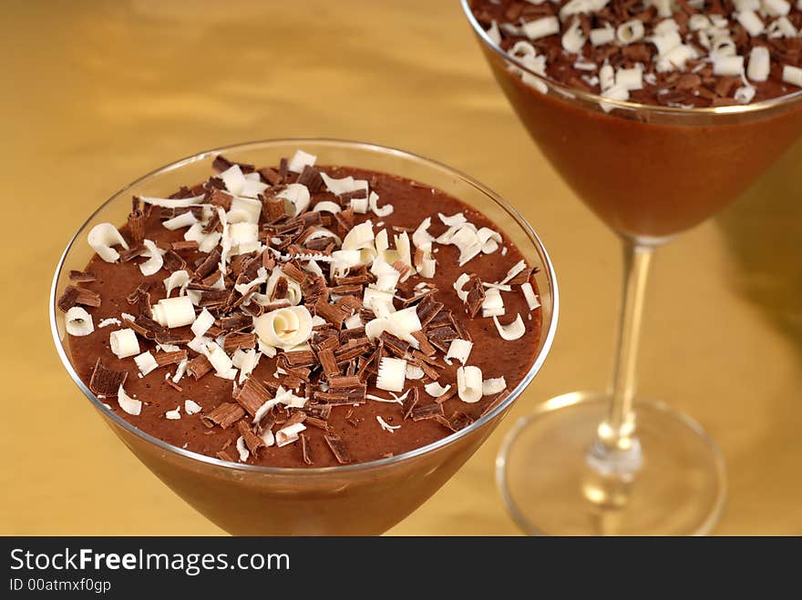Chocolate pudding with chocolate curls in martini glasses on a gold background horizontal view
