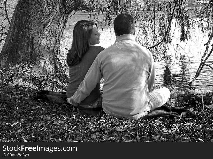 Young couple sitting under a tree. Young couple sitting under a tree