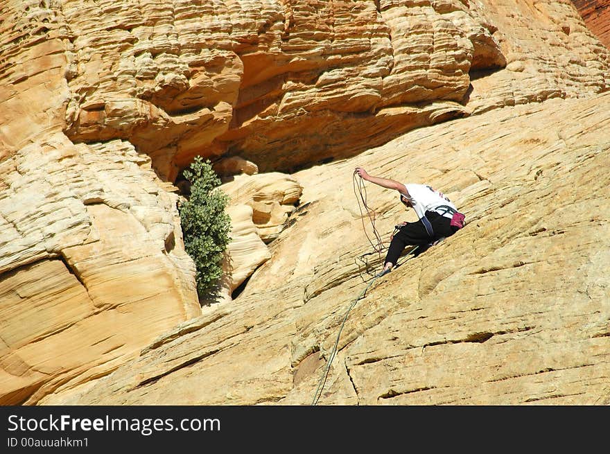 A guy checking his ropes while climbing a mountain. A guy checking his ropes while climbing a mountain.